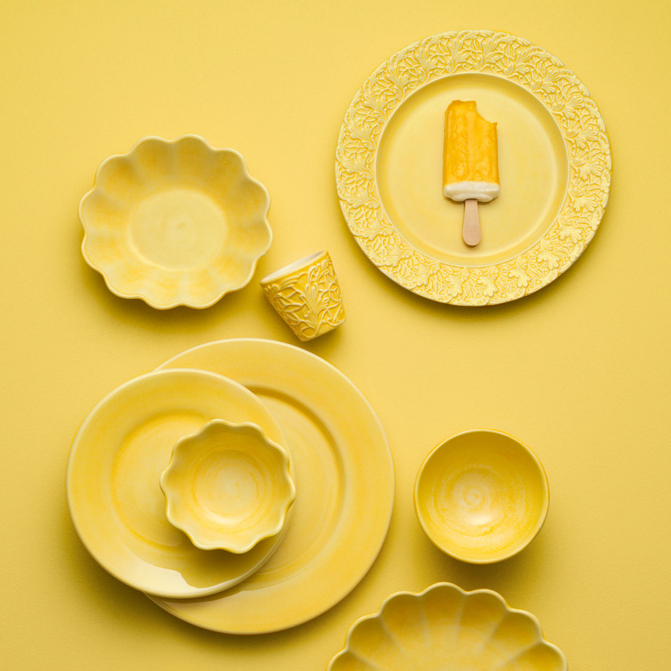 Yellow ceramic tableware set on a yellow background
