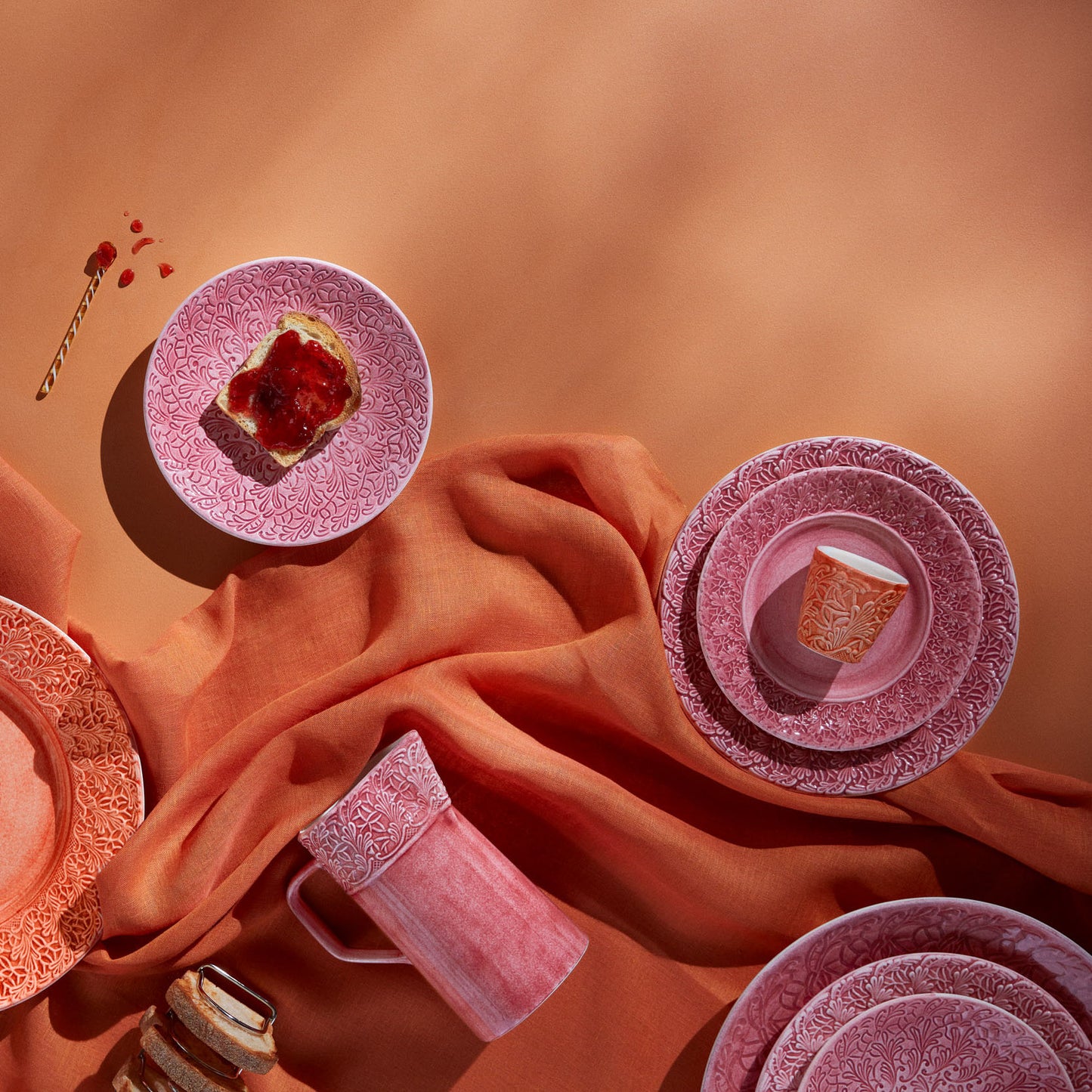Pink ceramic plates and cups on a textured orange surface