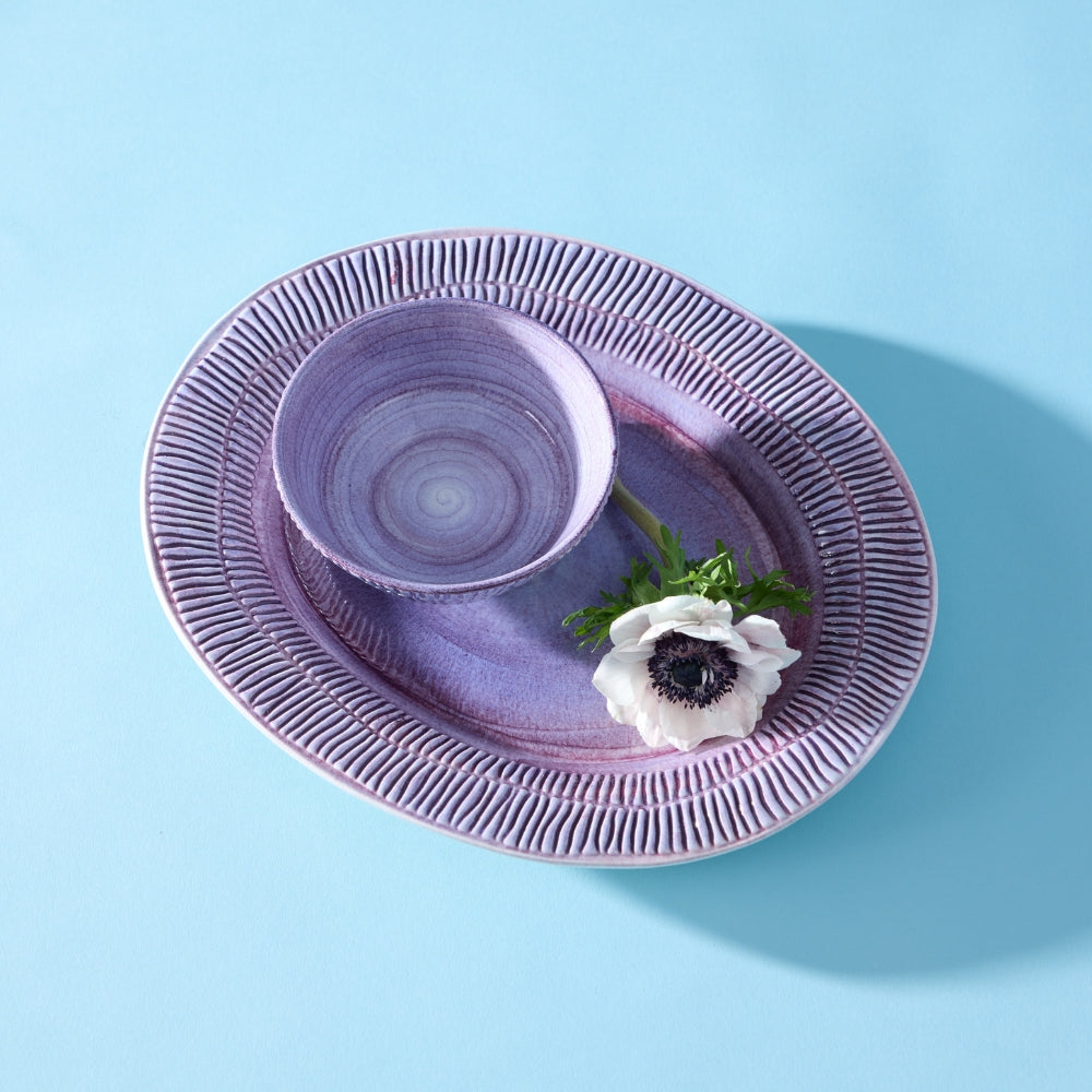 Purple ceramic plate with a matching bowl on a light blue background