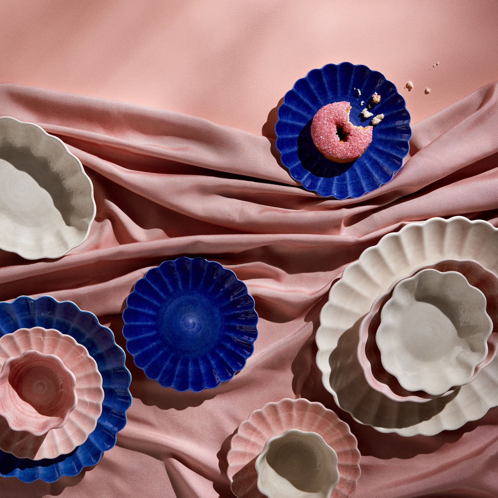 Decorative ceramic plates in blue, pink, and beige on a pink fabric background