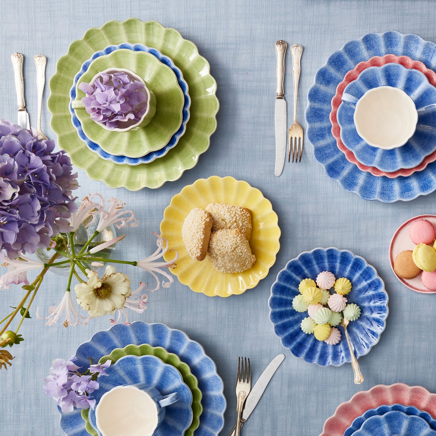 Colorful plates with pastries and flowers on a blue tablecloth