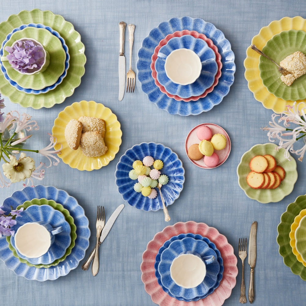 Colorful ceramic plates with food and cutlery on a blue tablecloth
