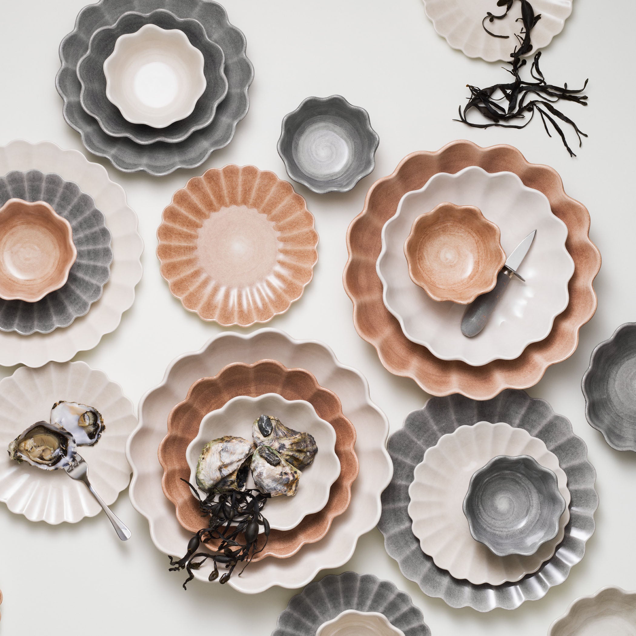 Collection of ceramic plates and bowls in various colors on a white background