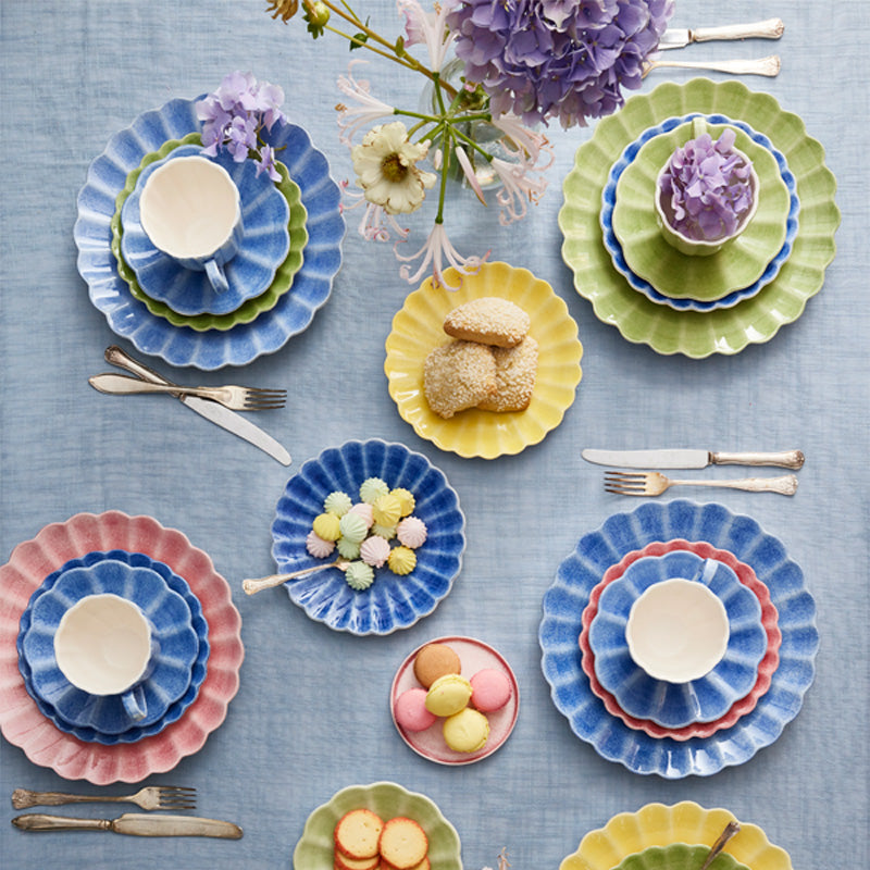 Colorful ceramic plates with floral decorations on a blue tablecloth.