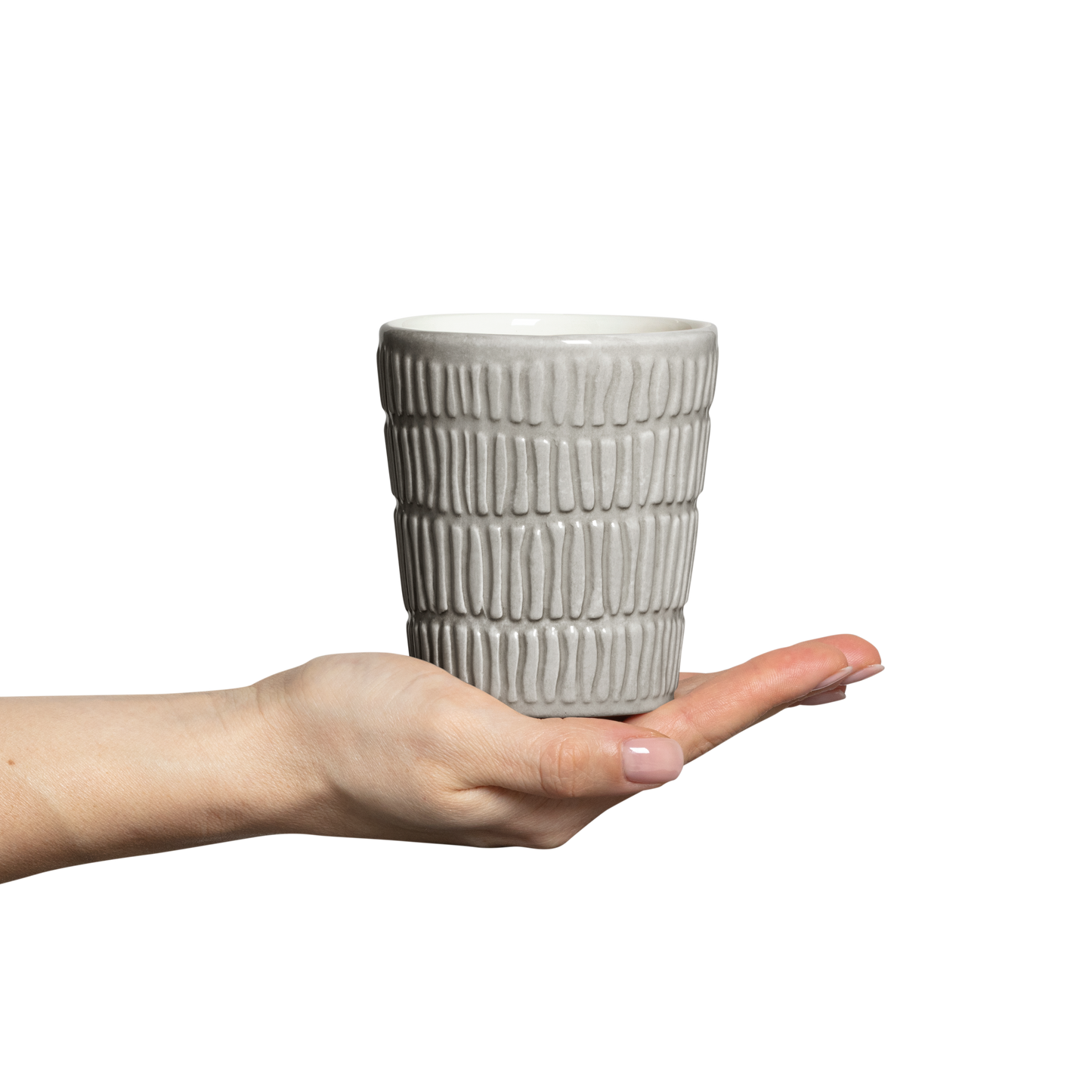 Hand holding a textured ceramic cup against a white background