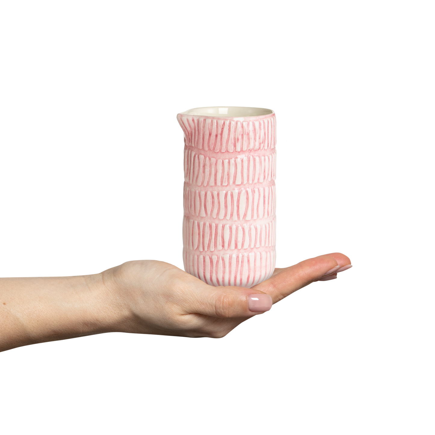 Pink textured ceramic jug held in a hand against a white background