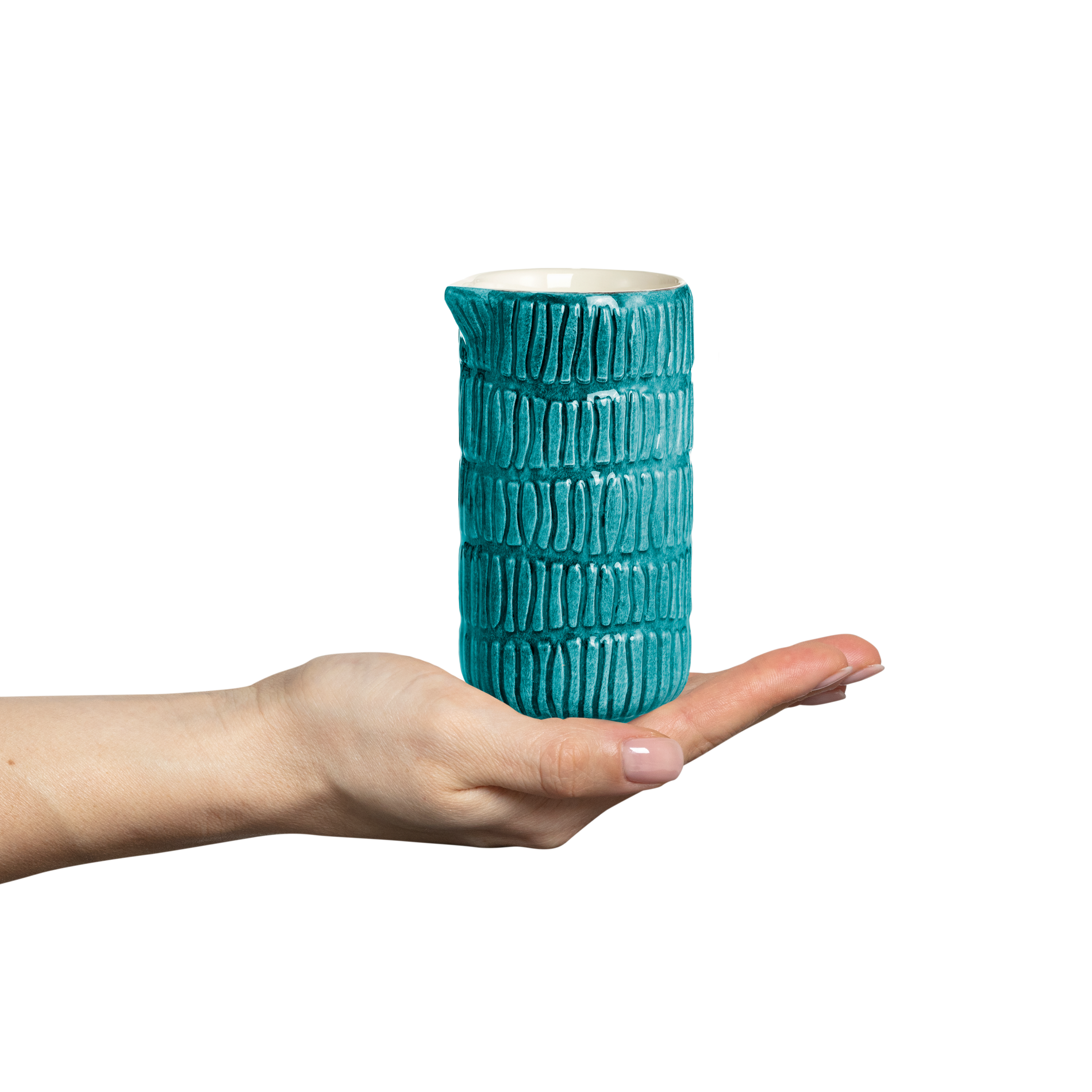 Ceramic jug held in a hand against a white background