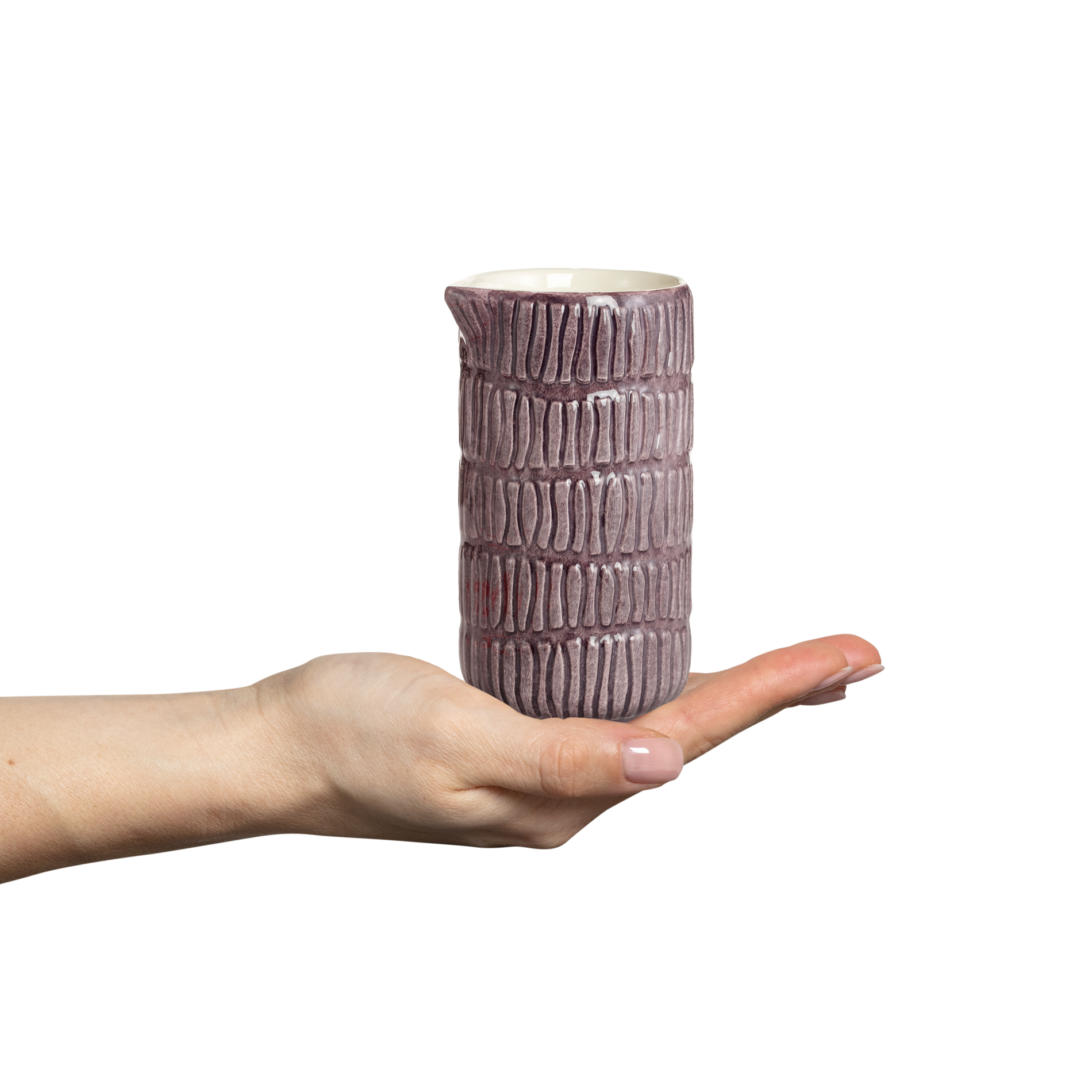Hand holding a textured ceramic jug against a white background