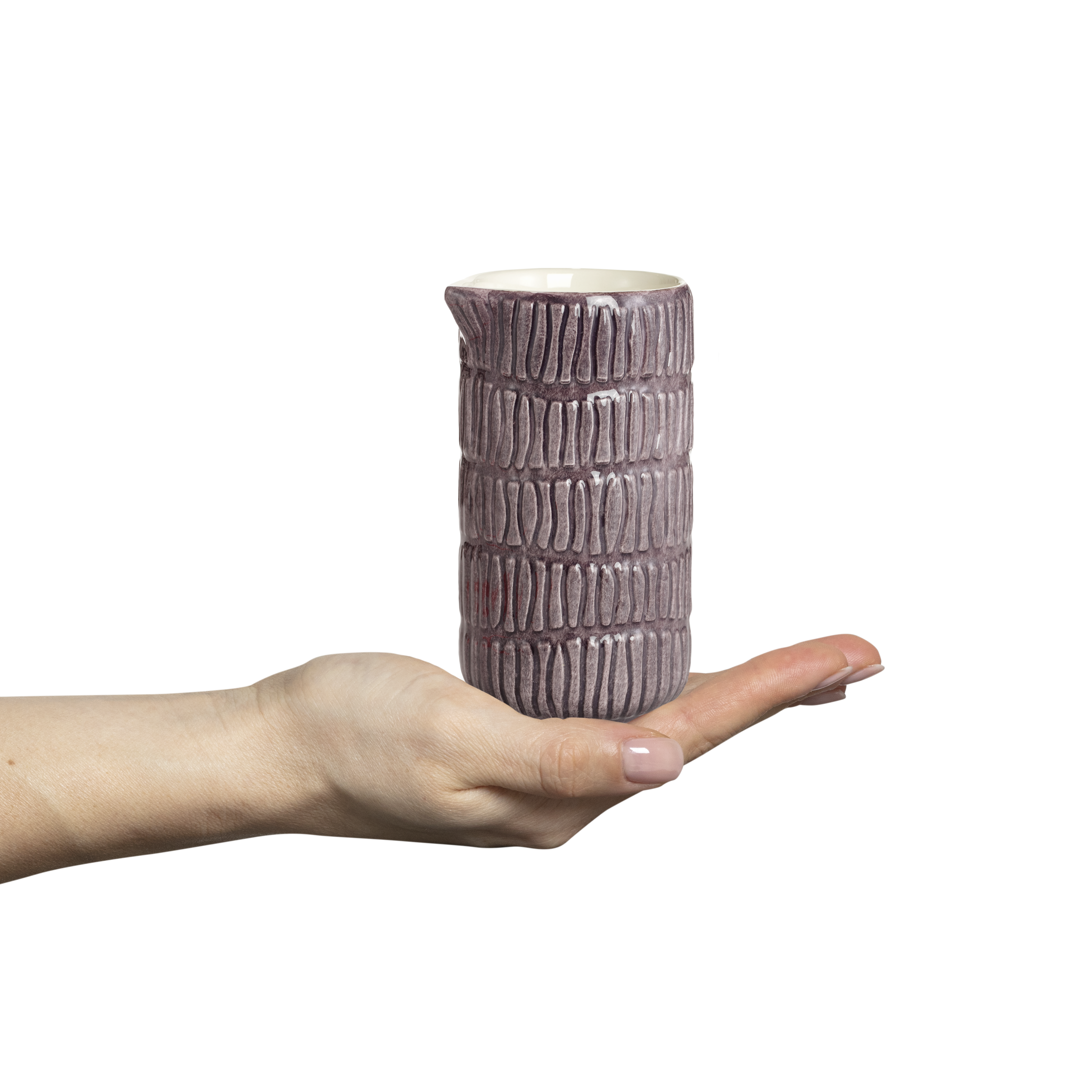 Hand holding a textured ceramic jug against a white background
