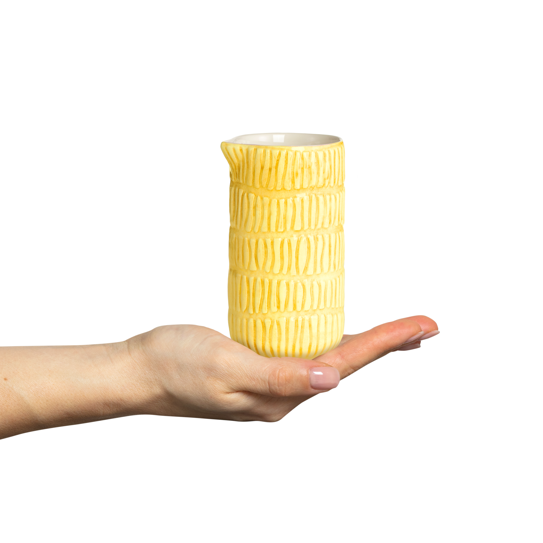 Yellow textured ceramic pitcher held in a hand against a white background