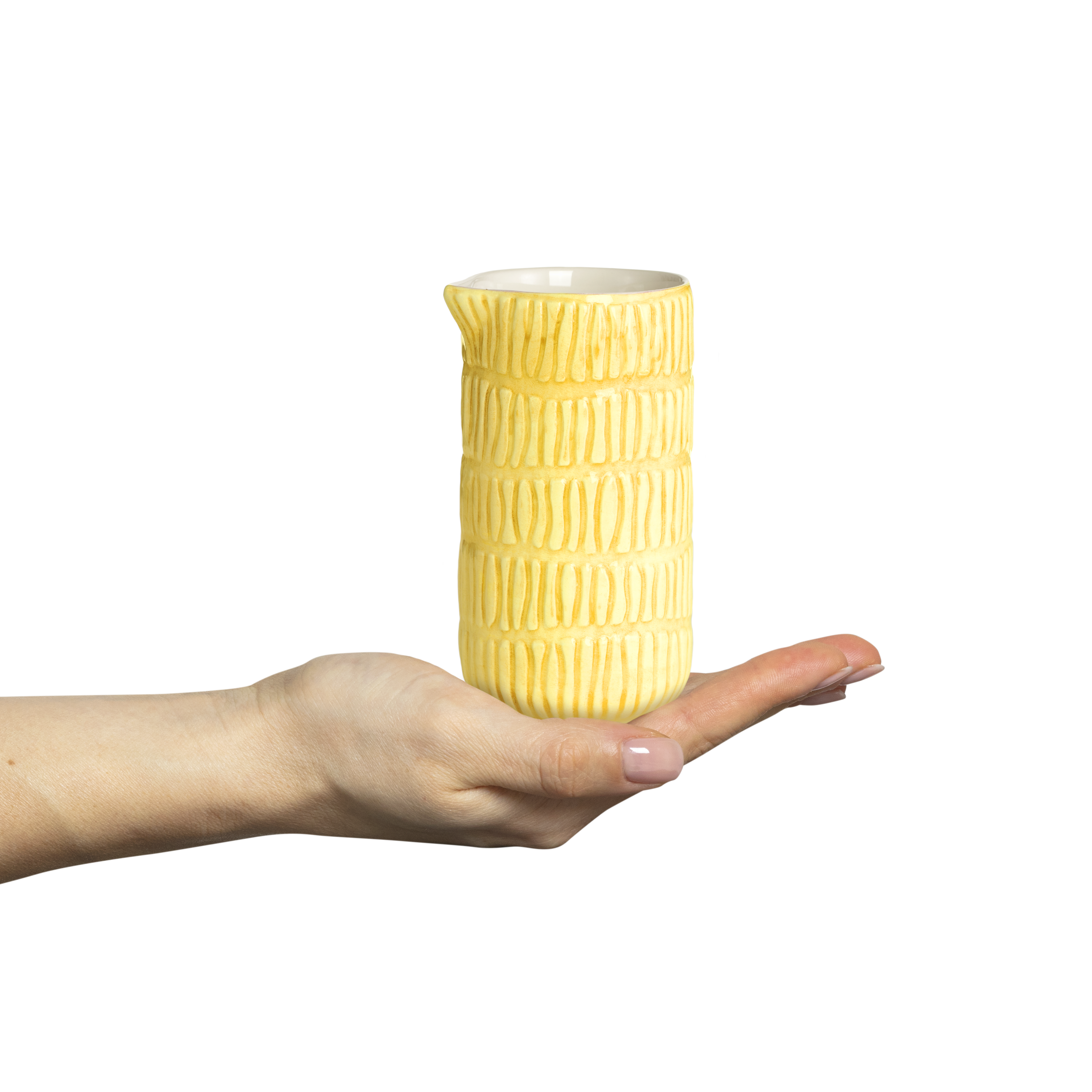 Yellow textured ceramic pitcher held in a hand against a white background