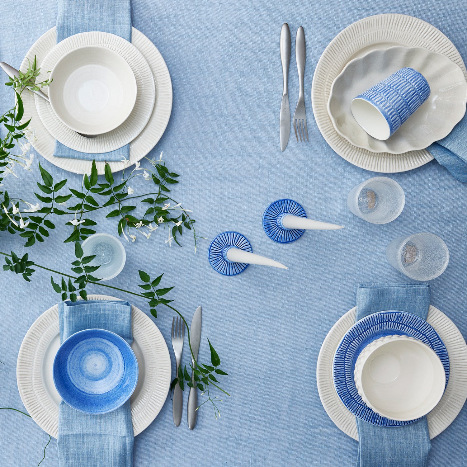 Table setting with blue and sand ceramics on a light blue tablecloth.