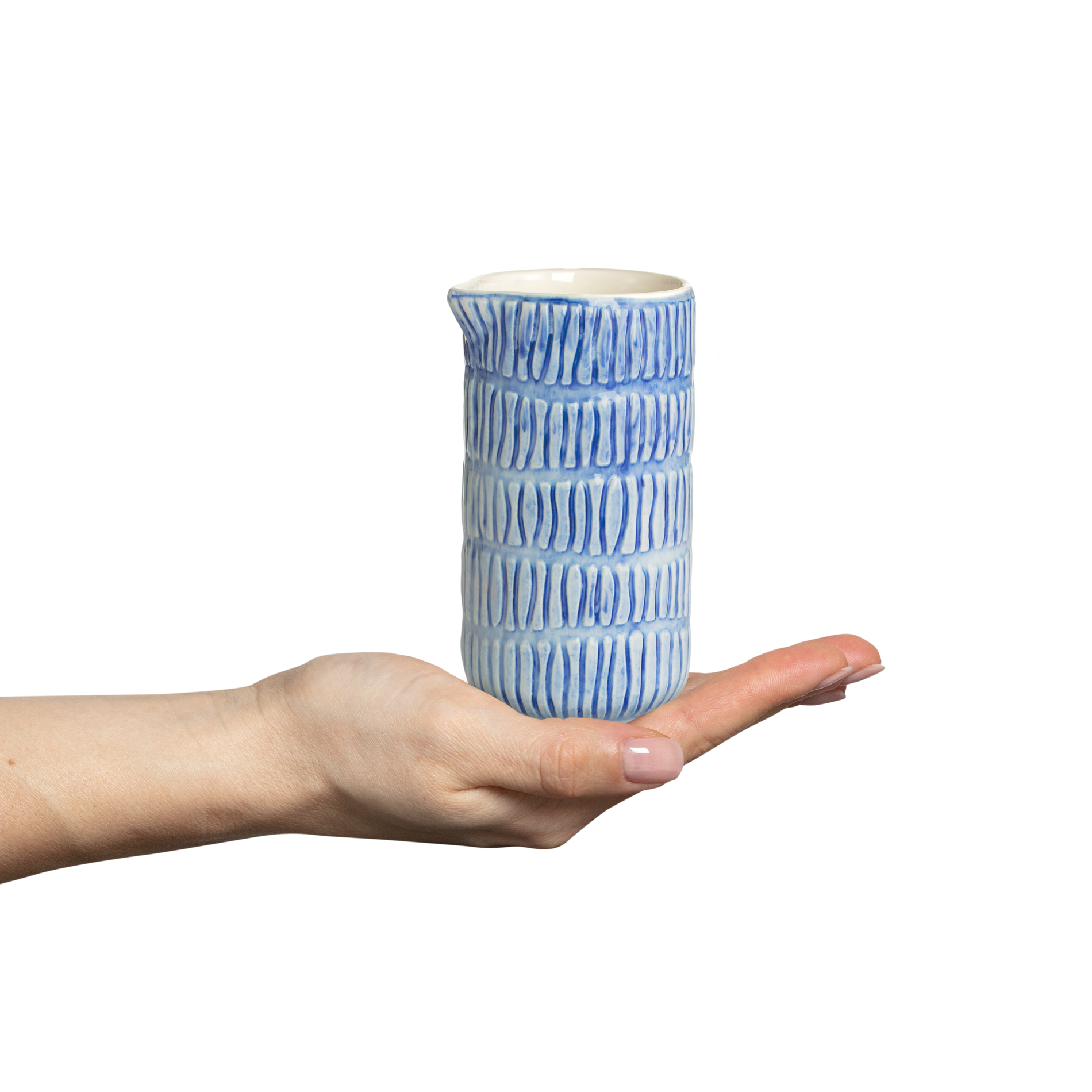 Hand holding a blue and white ceramic jug against a white background