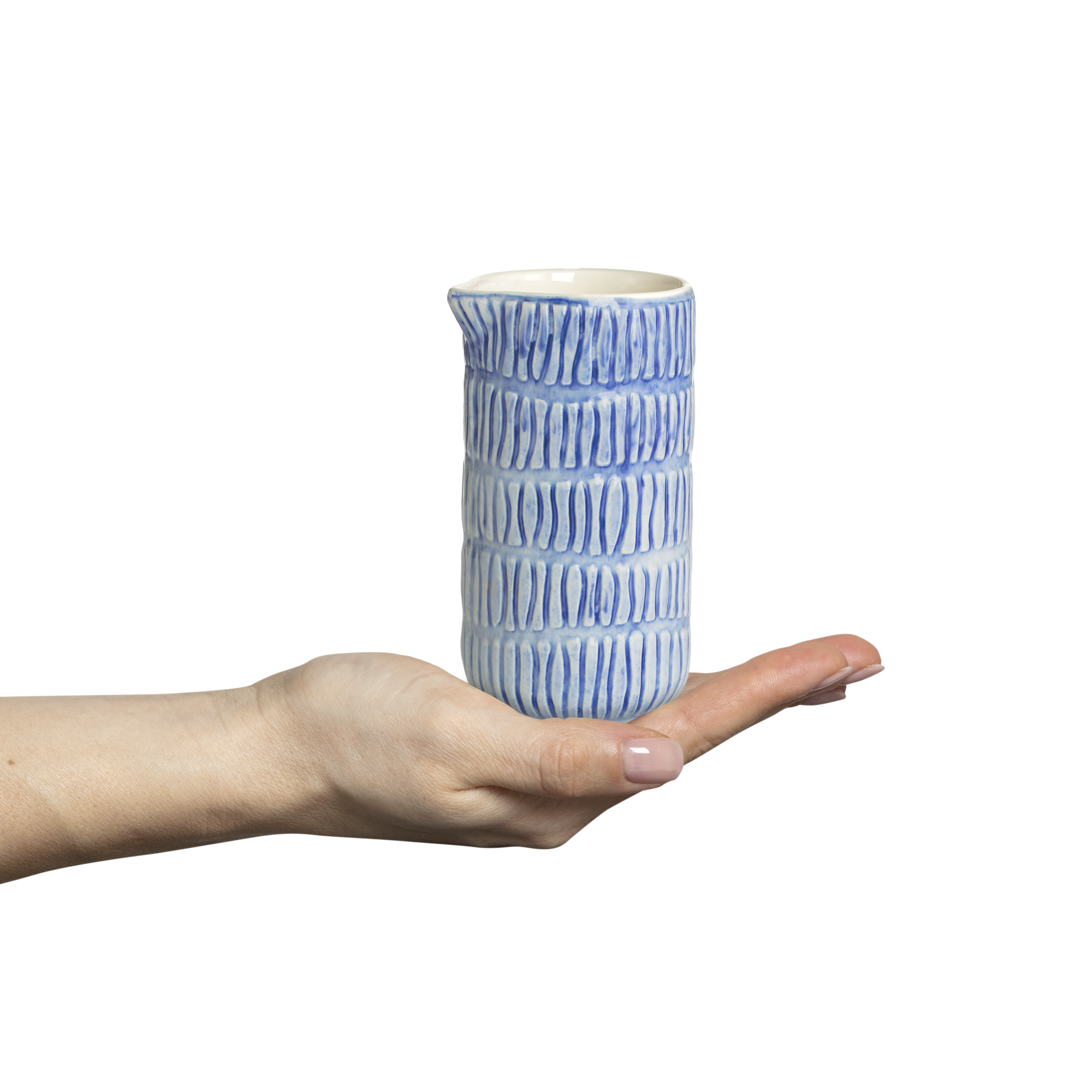 Hand holding a blue and white ceramic jug against a white background