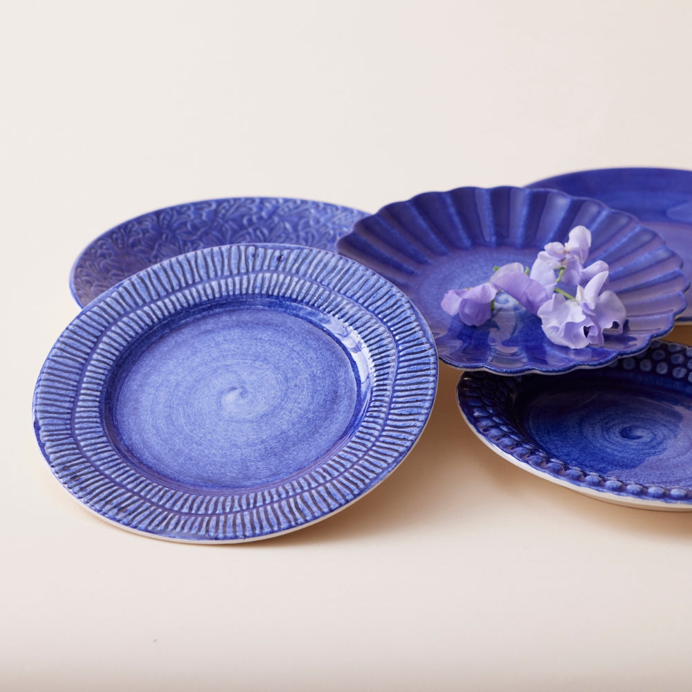 Set of blue ceramic plates with textured designs on a beige background