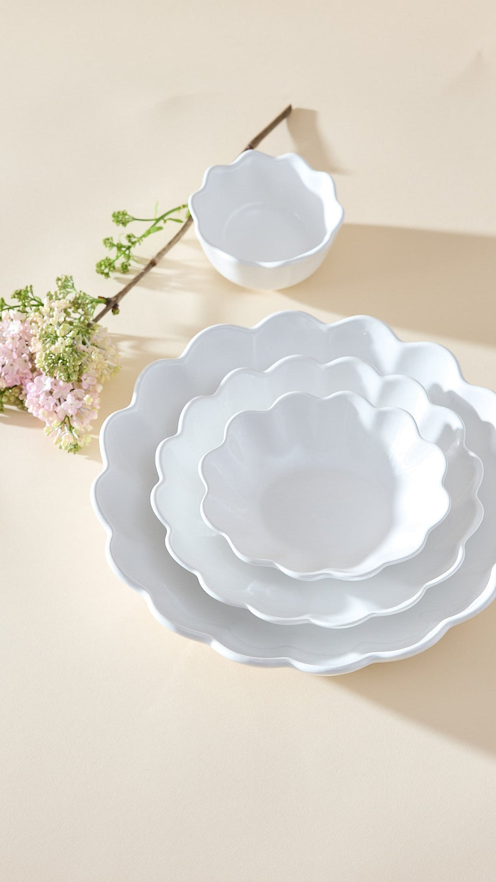 Set of white ceramic bowls with scalloped edges on a beige background